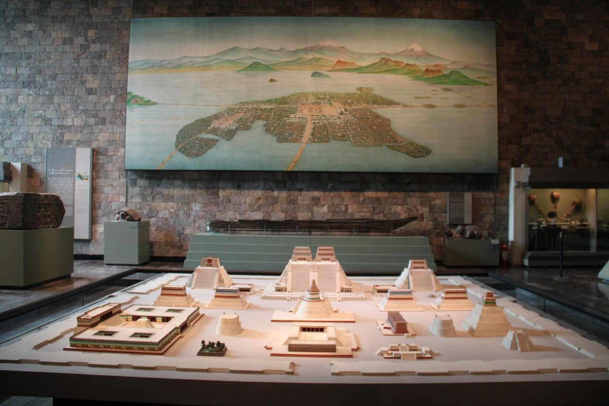 Model obřadního okrsku Tenochtitlánu v Národním antropologickém muzeu v Ciudad de México; vzadu uprostřed dvojitý chrám Templo Mayor. Na stěně obraz města na ostrově v jezeře Texcoco, spojeného hrázemi s pevninou.
