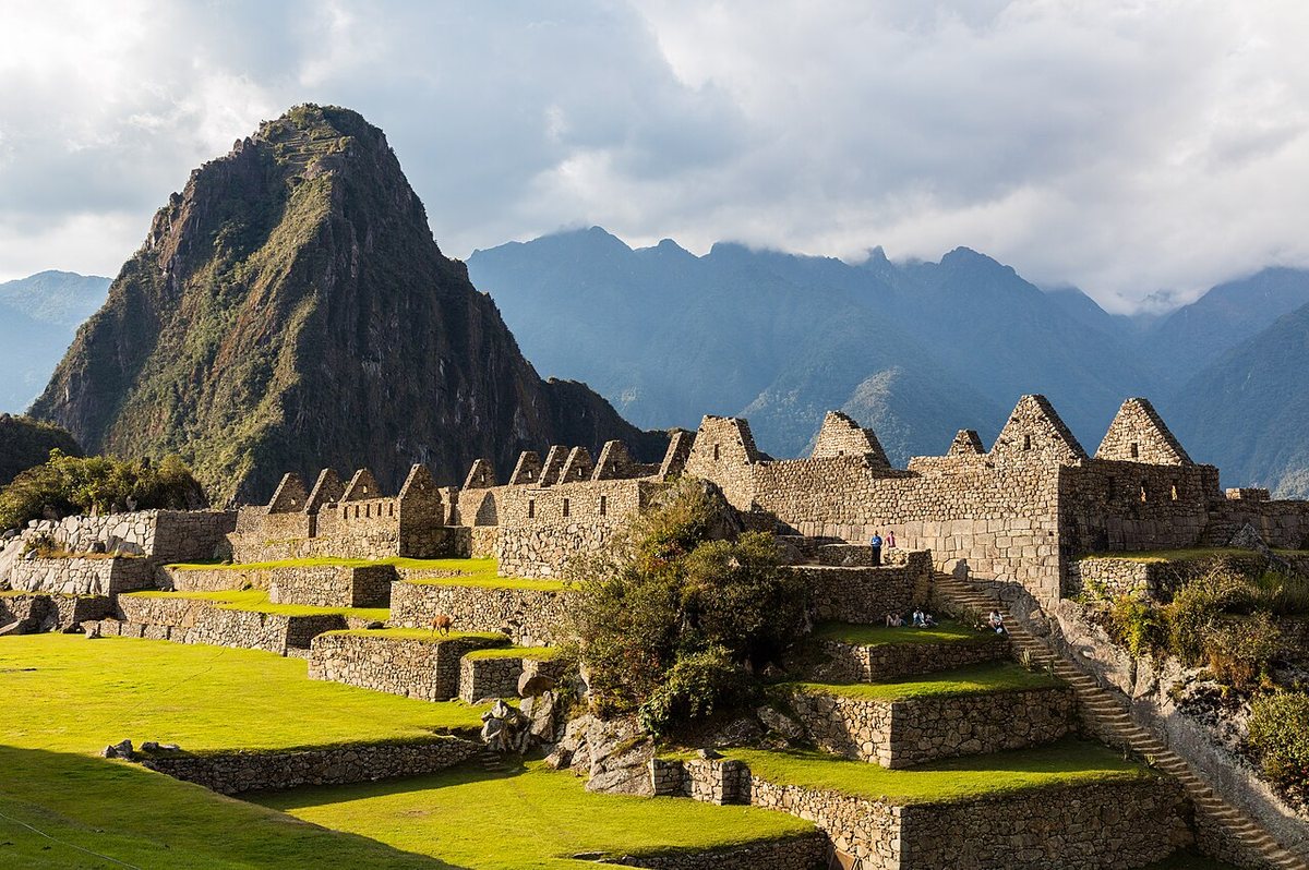 Machu Picchu, incké sídlo z 15. století na horském hřebeni asi 2430 metrů nad mořem nad údolím Urubamby, opuštěné zhruba o sto let později. V popředí terasy a kamenné domy, v pozadí hora Huayna Picchu.