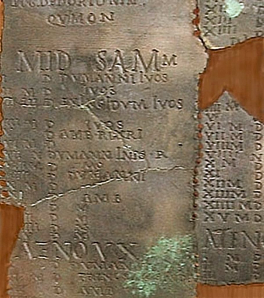 Detail kalendáře z Coligny: záhlaví měsíce Samonios (MID SAMON…), pod ním dny s římskými číslicemi a poznámkami jako DVMANNI IVOS, dole slovo ATENOVX, které dělí měsíc na dvě poloviny. Vpravo řada otvorů pro kolíček.