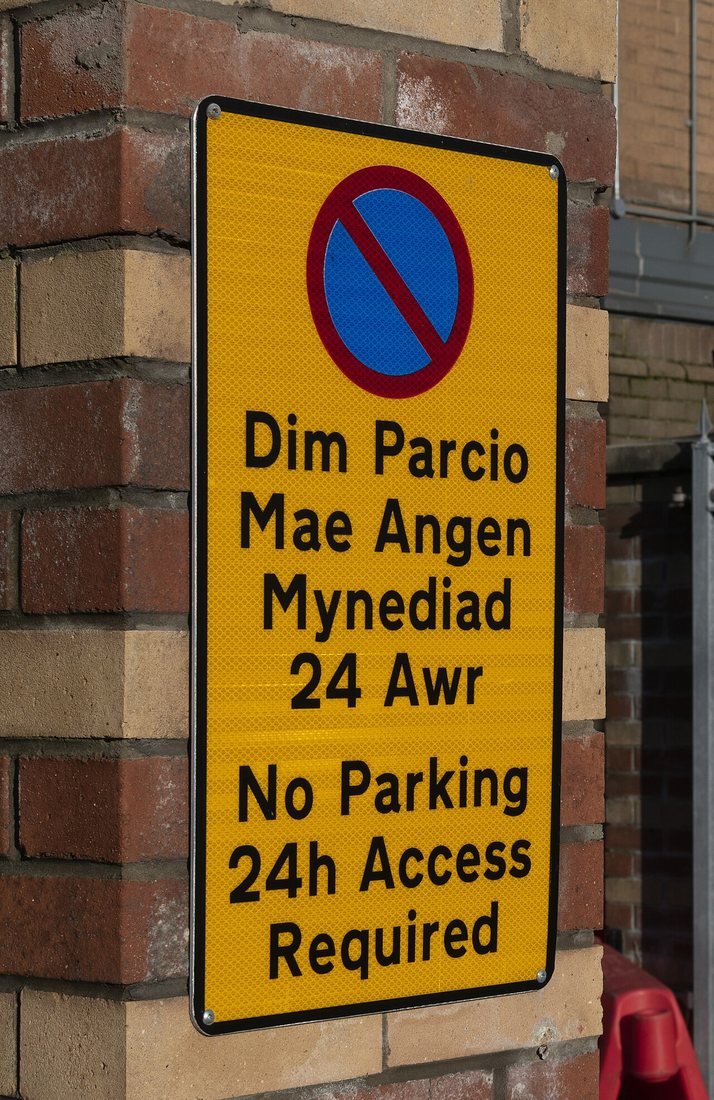 Dvojjazyčný zákaz parkování na náměstí Loudoun Square v cardiffské čtvrti Butetown: Dim Parcio – No Parking.