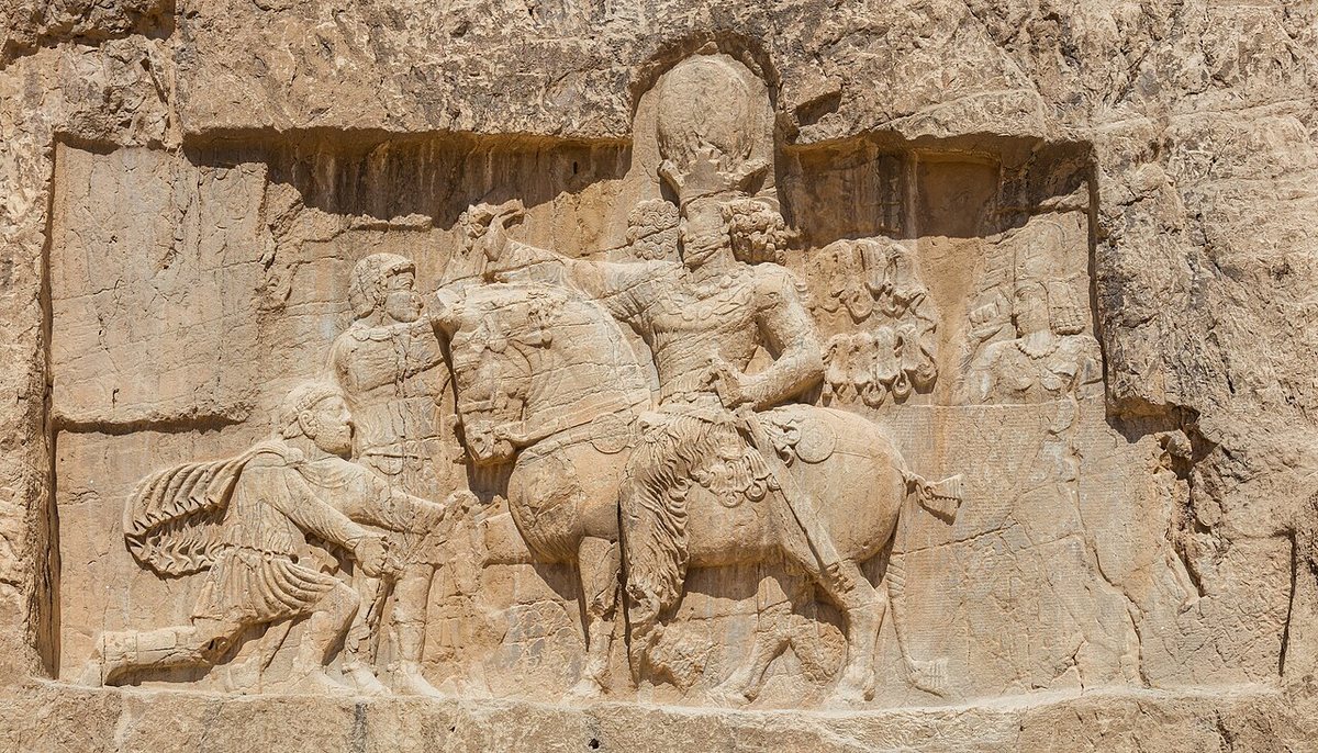 Reliéf triumfu Šápúra I. nad Římem v Naqš-e Rostamu (3. století n. l.). Před králem klečí Říman a dalšího drží Šápúr za zápěstí; obvykle se v nich vidí císaři Filip Arab a Valerianus, přiřazení postav je ale sporné.