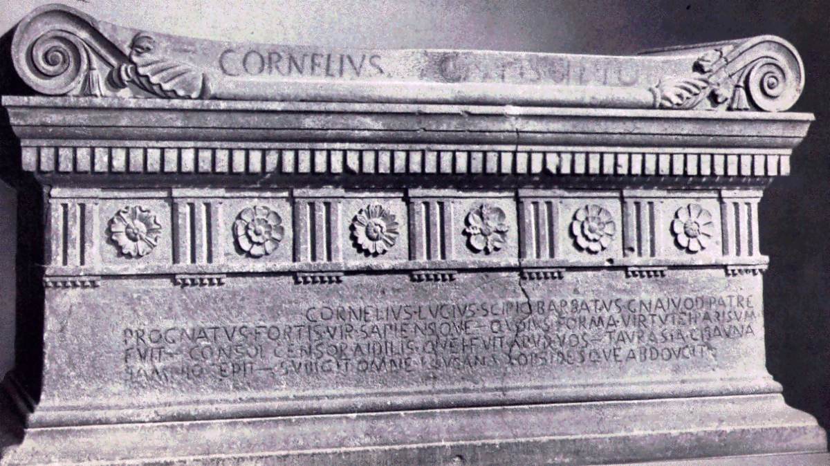 Sarkofág Lucia Cornelia Scipiona Barbata, konzula roku 298 př. n. l., z hrobky Scipionů u Via Appia, dnes ve Vatikánských muzeích. Na víku je jméno CORNELIVS, na přední stěně veršovaný nápis ve staré latině.