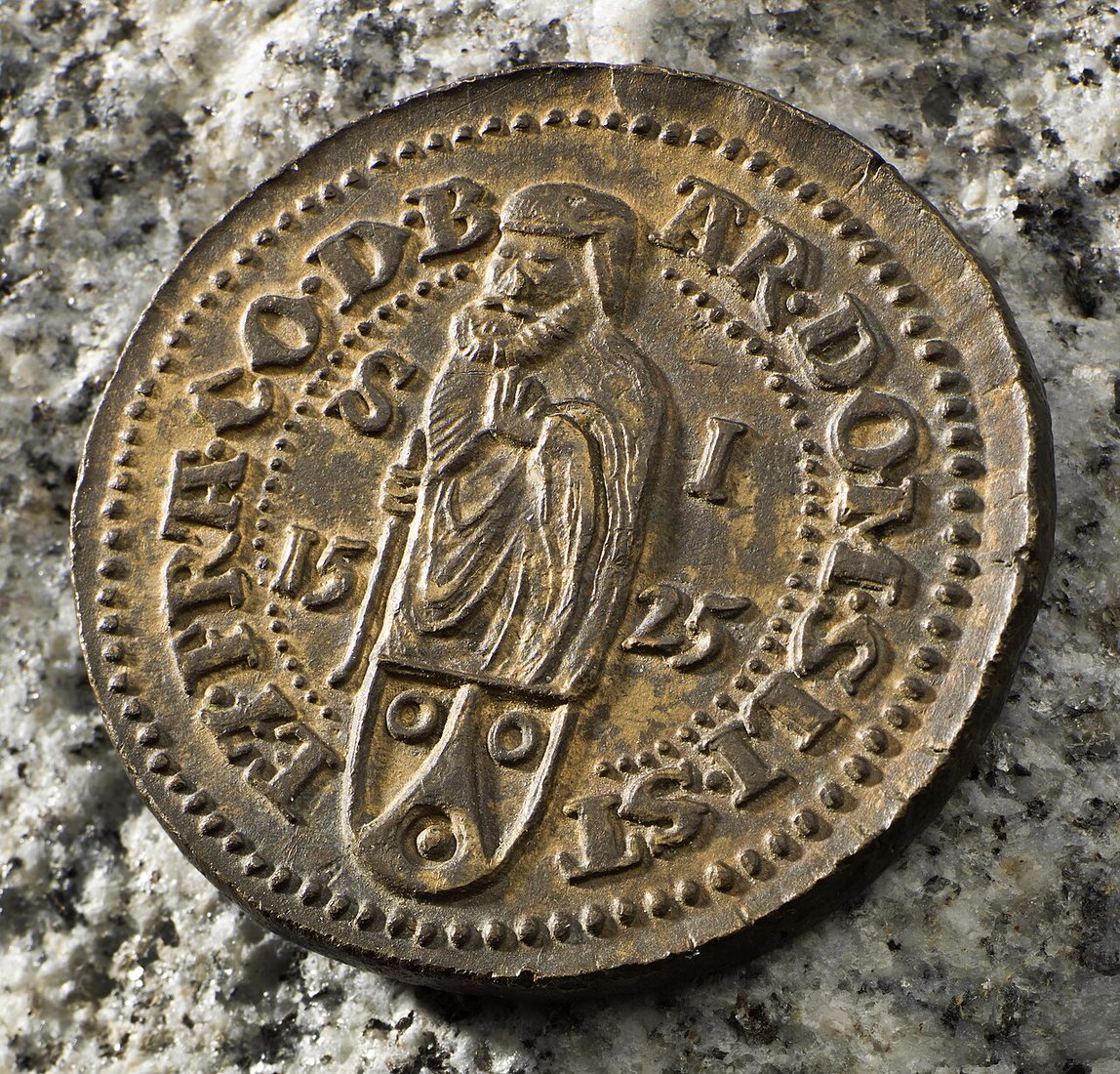 Druhá strana téže mince: svatý Jáchym nad erbem Šliků a letopočet 1525.
